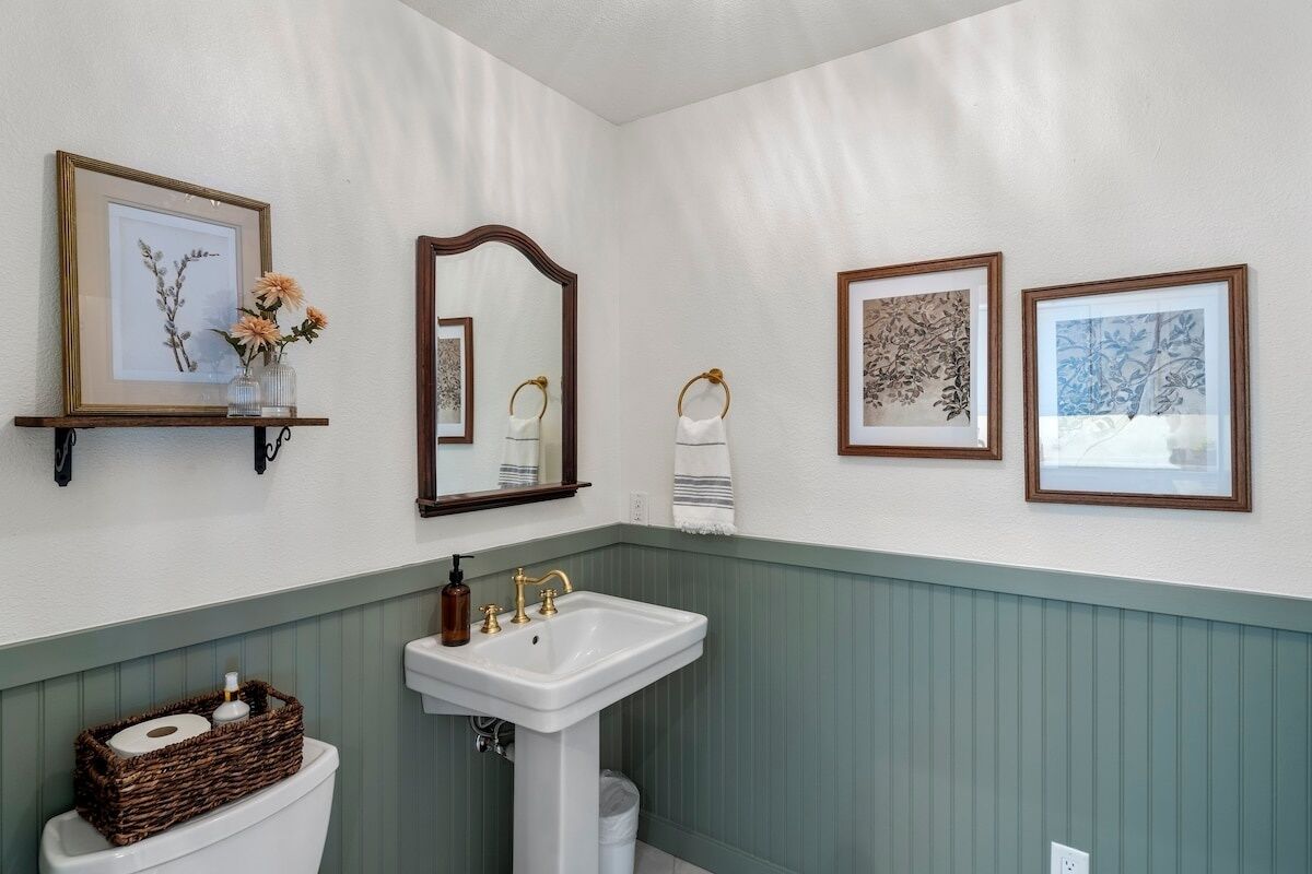 A bathroom with a white sink, a mirror, and framed pictures on the wall.