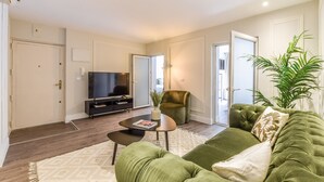 A living room with a green sofa, a small coffee table, a TV, and a plant. - Spectacular design apartment in the center SB 1 (Madrid)
