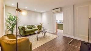 A living room with a green sofa, a gold armchair, a coffee table, and a floor lamp. - Spectacular design apartment in the center SB 1 (Madrid)