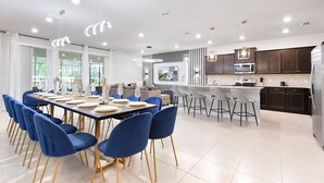 Une cuisine moderne avec des meubles de couleur sombre, un réfrigérateur en acier inoxydable et un grand îlot central doté de tabourets de bar.