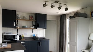 Uma cozinha compacta com armários escuros, micro-ondas e um pequeno espaço para refeições.