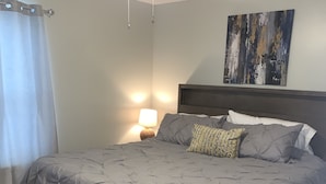 Ein Schlafzimmer mit einem Bett, einem Nachttisch, einer Lampe, einem Deckenventilator und einem Bild an der Wand.