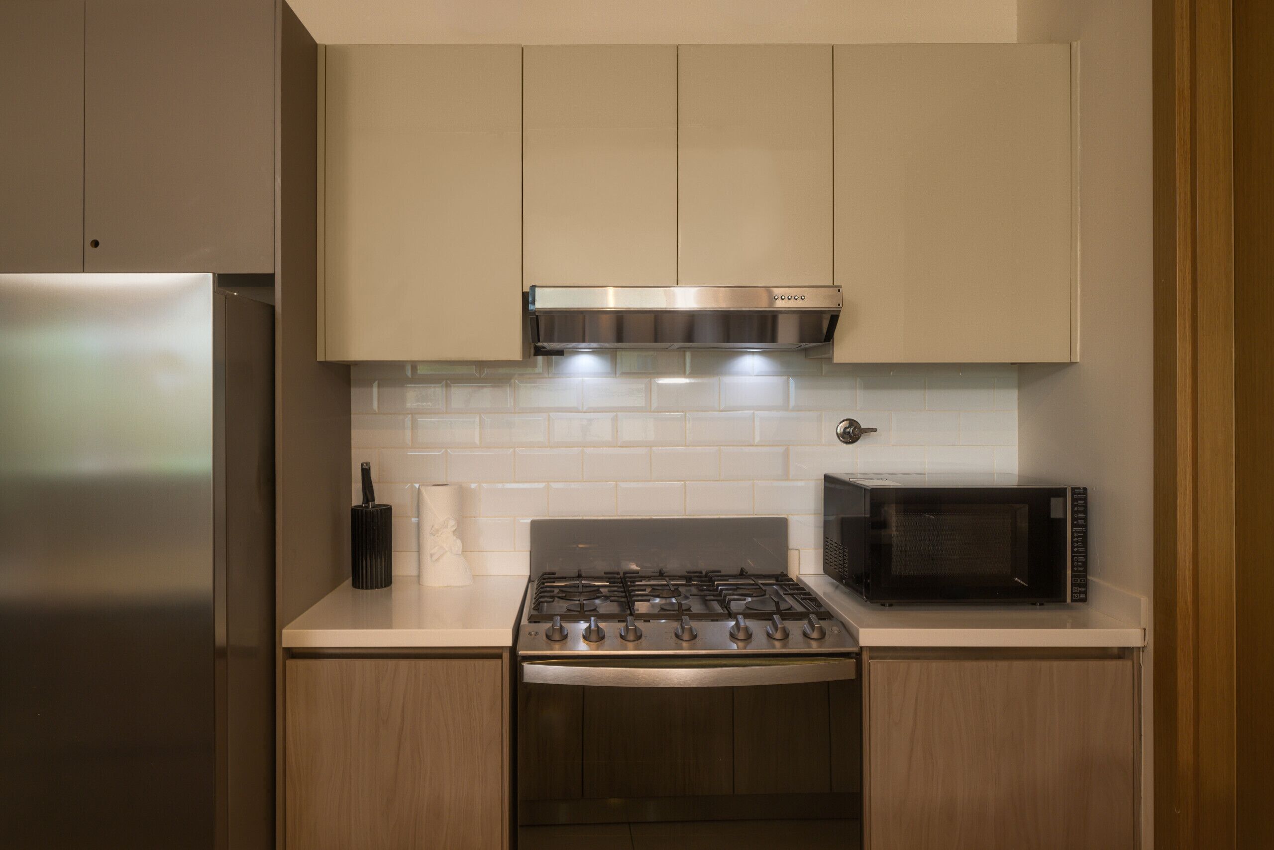 A kitchen with a stainless steel stove, a microwave, and wooden cabinets.
