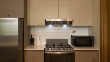 A kitchen with a stainless steel stove, a microwave, and wooden cabinets.