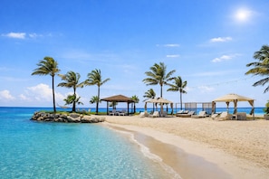 Uma praia com águas azul-claras, palmeiras e guarda-sóis.