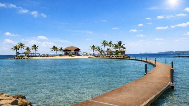 A wooden pier leading to a tropical island with a thatched-roof building and palm trees.