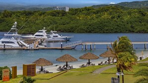 A marina with yachts docked, a beach with umbrellas, and a sign for Ocho Nudos.