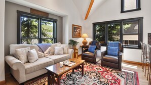 Un salon comprenant un canapé, deux fauteuils, une table basse et un tapis à motifs.