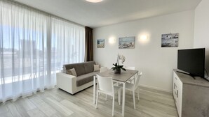 A modern living room with a sofa, dining table, chairs, and artwork on the walls.
