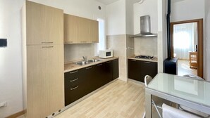 Cocina compacta con microondas, estufa y lavamanos.