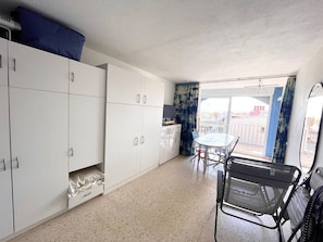 A compact kitchen with white cabinets, a dining table with chairs, and a balcony with a view.