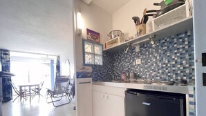 Cozinha compacta com lava-louças, painel de azulejos e área de refeições com cadeira e mesa.