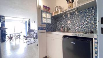 Een koelkast, een microgolfoven, een oven, kookgerei, borden en bestek