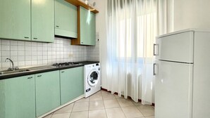 Una cocina con gabinetes verdes, una lavadora y un refrigerador.