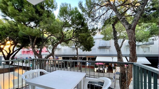 Terraza al aire libre con una mesa y sillas, rodeada de árboles y edificios al fondo.
