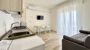 A modern kitchen with a built-in washing machine, a dining area with a table and chairs, and a living area with a sofa.