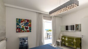 A bedroom with a bed, a dresser, a TV, and a painting on the wall.