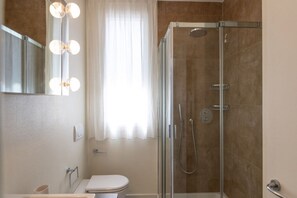 Une salle de bain moderne avec une douche à parois de verre, des toilettes et un meuble-lavabo avec un miroir.
