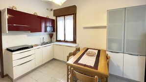 Una cocina compacta con armarios blancos, una mesa de madera y un microondas integrado.