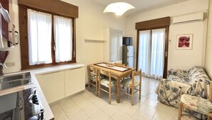 Una cocina compacta con una mesa de comedor, sillas, horno integrado y televisor.