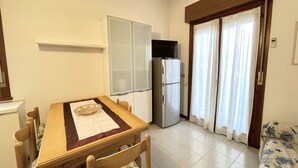 Una cocina compacta con una mesa de comedor, sillas, un refrigerador y un televisor.