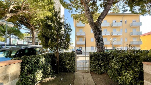 Una entrada porticada a un edificio residencial con un sendero pavimentado que conduce a la puerta.