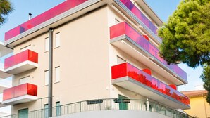 A multi-story building with balconies, a flat roof, and a clear sky.