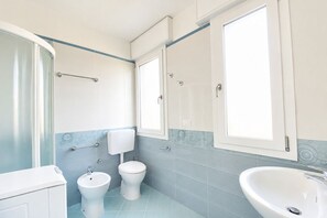 Ein Badezimmer mit Dusche, Toilette, Bidet und Waschbecken.