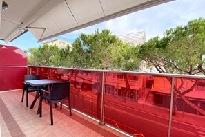 Un balcon doté d’une balustrade en verre, de deux chaises et d’une table.