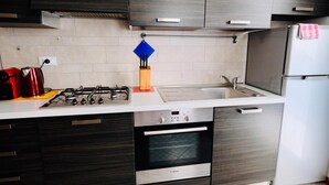 Eine moderne Küche mit dunklen Holzschränken, einem Edelstahl-Bosch-Ofen, einer weißen Arbeitsplatte und einem roten Wasserkocher.