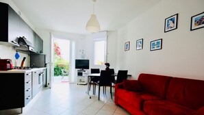 Eine moderne Küche mit Essbereich, einem roten Sofa und einem Fernseher.