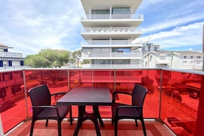 Uma varanda com mesa e cadeiras, com vista para uma área residencial com edifícios altos.