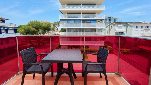 Un balcon avec une table et des chaises, donnant sur un immeuble doté de nombreux balcons.