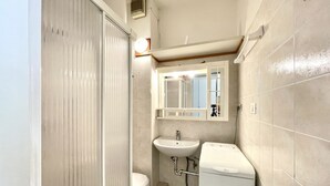 Een kleine badkamer met toilet, wastafel en een compacte wasmachine.