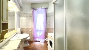 Un baño con lavamanos, inodoro y lavadora.