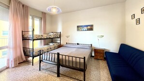 Un dormitorio con literas, un sofá, una lámpara y un cuadro en la pared.