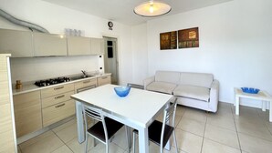 Une cuisine compacte comprenant une table à manger et des chaises, un canapé et une petite table d’appoint.
