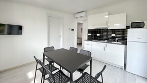 Cozinha moderna com armários brancos, bancada preta e geladeira branca.