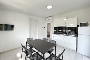 Een moderne keuken met witte kasten, een zwart aanrecht en een witte koelkast.