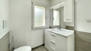 Uma casa de banho moderna com sanita, lavatório e espelho.