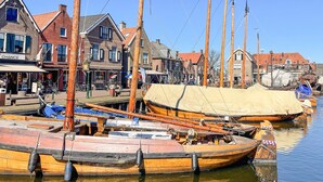 A harbor with wooden boats docked, buildings with red roofs, and a clear sky. - Stunning house in Spakenburg (Spakenburg)