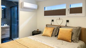 A bedroom with a bed, a nightstand, a wall-mounted air conditioner, and a window with blinds. - Stunning house in Spakenburg (Spakenburg)