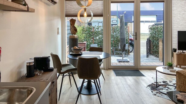 A modern kitchen with a dining area, large sliding glass doors to an outdoor patio, and a TV on a wooden stand. - Stunning house in Spakenburg (Spakenburg)