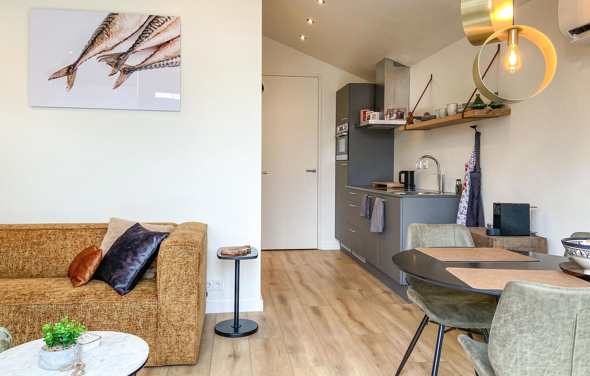 Un salon moderne avec un canapé, une petite table d’appoint et un coin repas comprenant une table et des chaises.