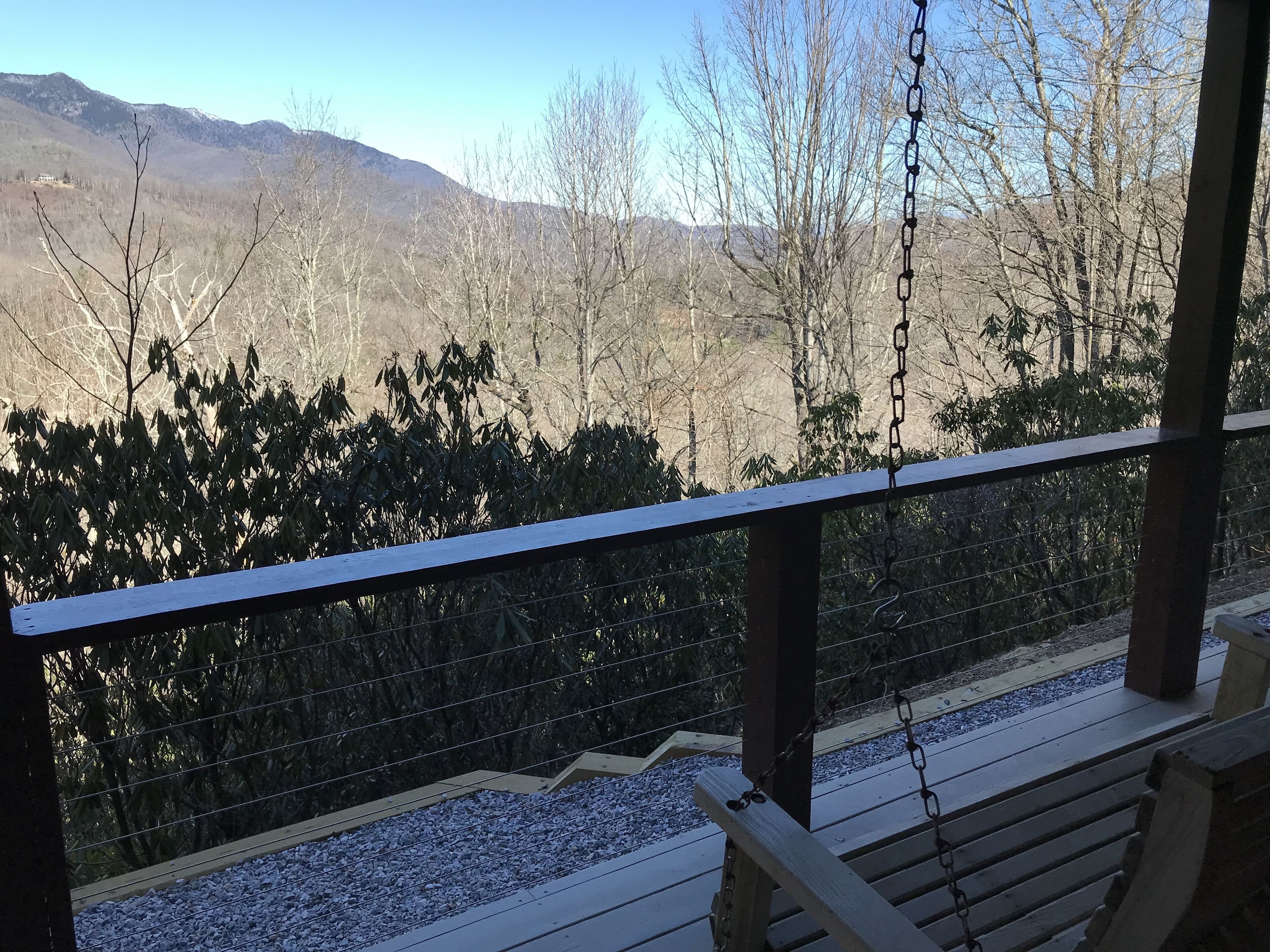 A wooden deck with a metal railing overlooking a mountainous landscape.
