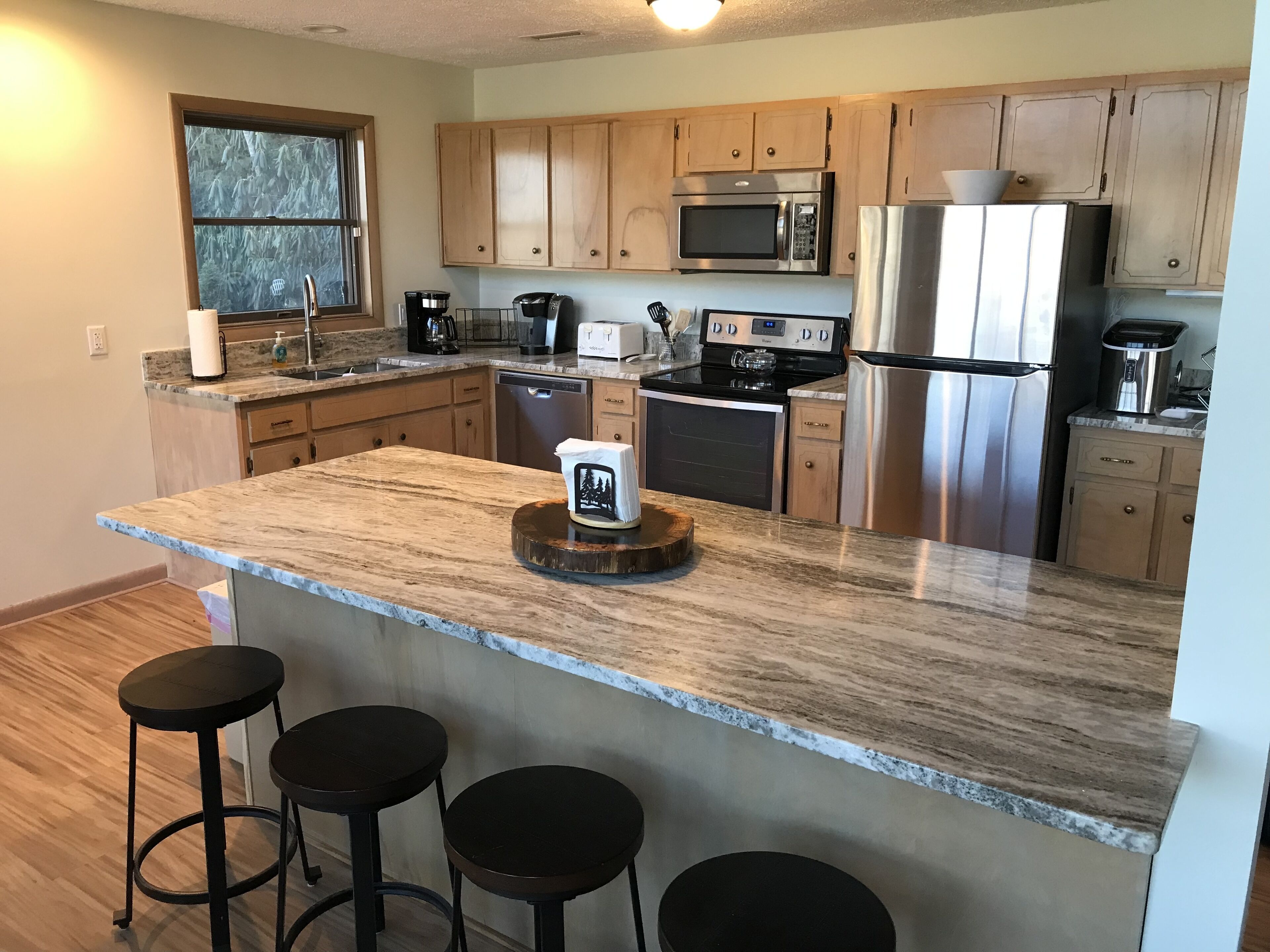 A modern kitchen with granite countertops, stainless steel appliances, and wooden cabinets.