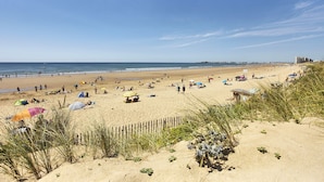 A sandy beach with people, umbrellas, and a wooden fence. - Panoramic View face Mer (Saint-Gilles-Croix-de-Vie)