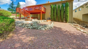 Una casa moderna con un patio in pietra, una scala in legno e vista sul paesaggio circostante.