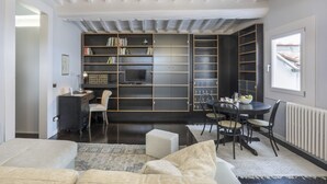 A modern living room with a sofa, a dining table with chairs, a TV, and built-in bookshelves. - Virgilio - Sweet Dreams in Florence (Firenze)
