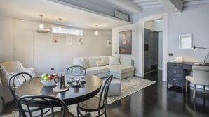 A modern living room with a dining area, a sofa, a coffee table, and a desk with a lamp. - Virgilio - Sweet Dreams in Florence (Firenze)
